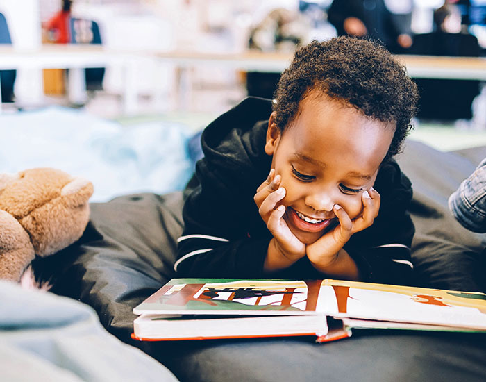 boy smiles at book while reading