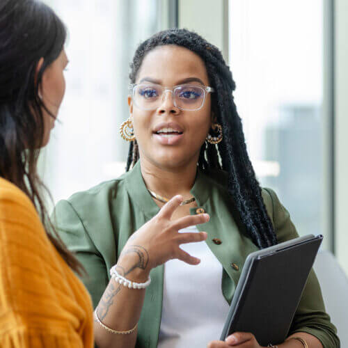 Two women having a conversation in business or educational setting