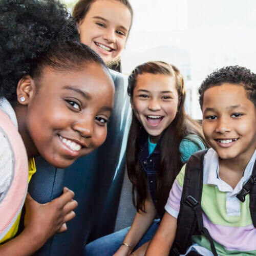 Group of middle school student on a bus smiling at the viewer