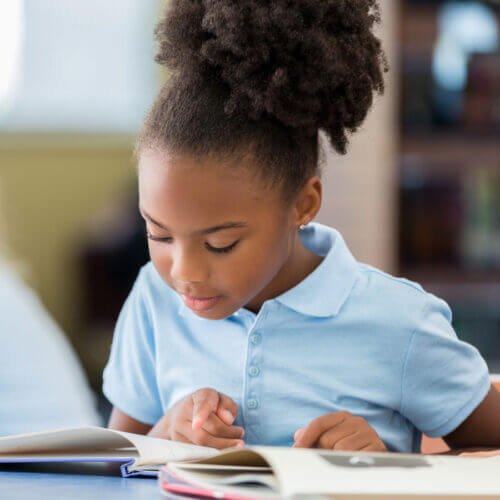 Young girl at school reading a book
